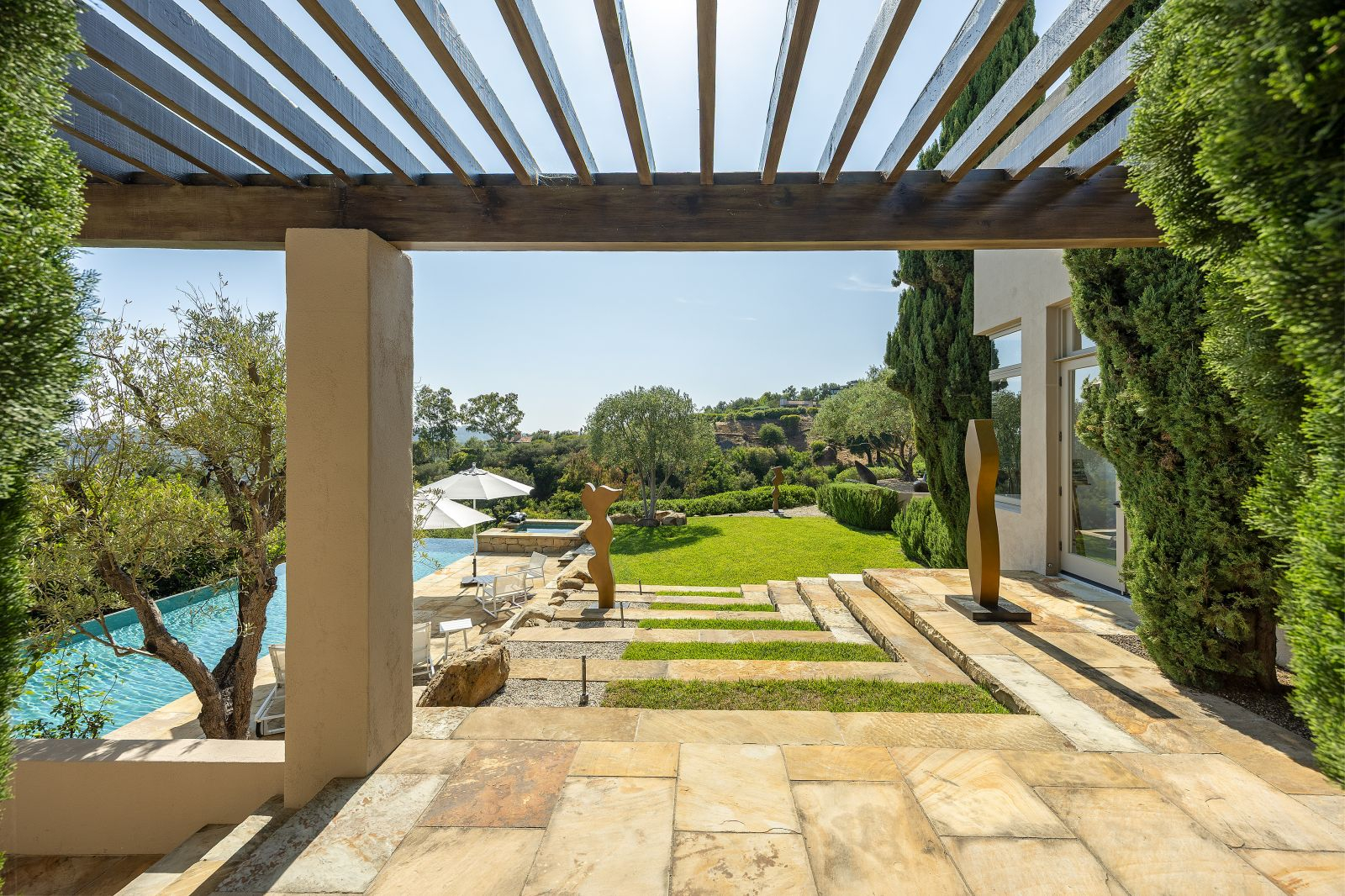 Outdoor terrace of a Montecito luxury home with pergola, stone steps, landscaped garden, and swimming pool.